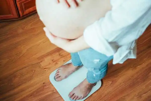 Image of woman weighing herself and experiencing weight gain through pregnancy Blandford Camp